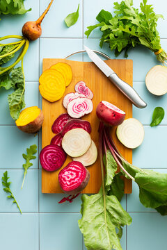Sliced beets of different colors on a cutting board, white, yellow, purple.