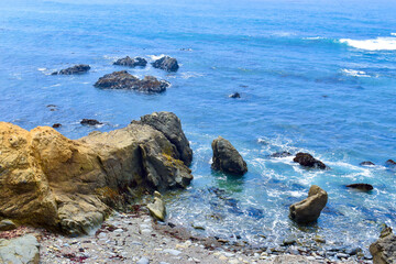 Beautiful blue ocean coast lined with rocks and incoming tide