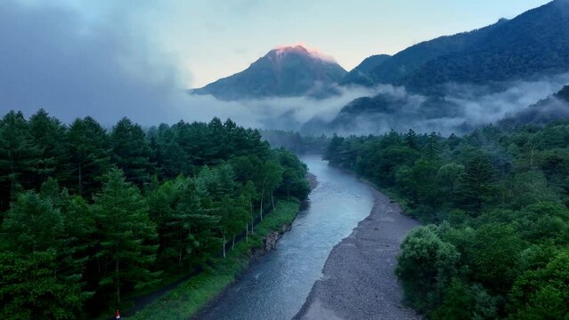 hiking in Japanese Alps, flying along a foggy morning on mountain river in Japanese Alps, Kamikochi national park, beautiful Japanese nature, establishing drone shot