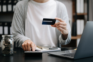Fototapeta premium businesswoman hand using smart phone, tablet payments and holding credit card online shopping, omni channel, digital tablet docking keyboard computer at office in sun light.