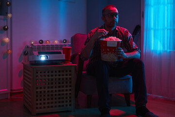 Man enjoying popcorn and juice while watching movie at home projector.