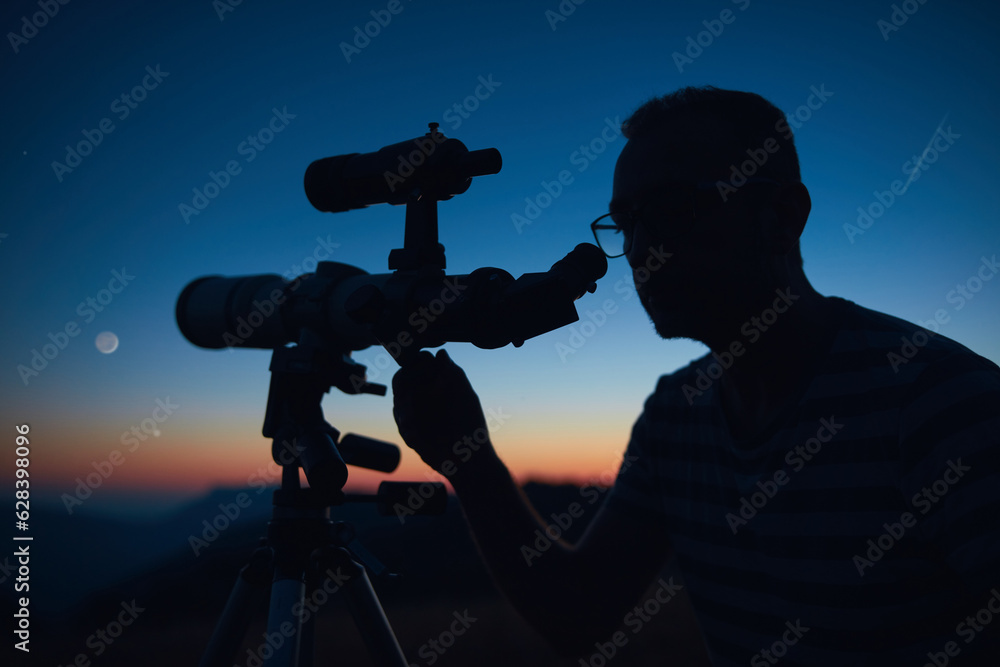 Wall mural astronomer looking at the starry skies and crescent moon with a telescope.