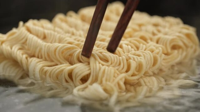 Cooking traditional noodle, Ramen. Instant noodles are mixed with chopsticks in boiled water