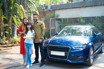 Fototapeta na wymiar Indian family standing with new car. girl holding puja thali in hand.