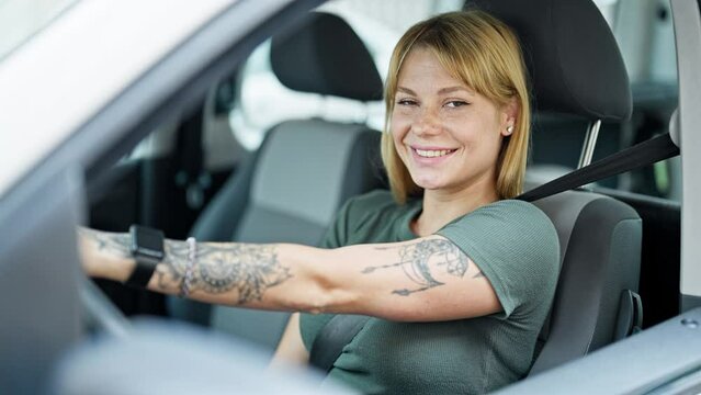Young blonde woman smiling confident driving car at street