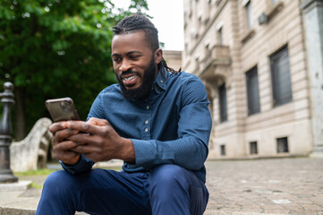 Fototapeta premium Dark-skinned young man in denim clothes with a phone in hand
