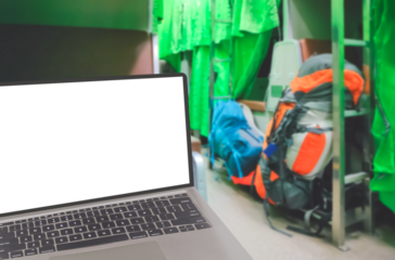 Close up of laptop with blank screen and blurred background of backpacks on aisle in sleeper train at night, png file