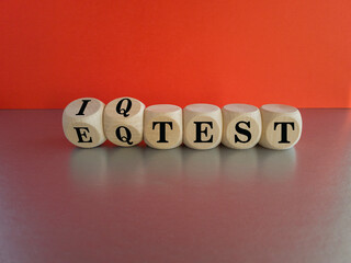 Dice form the expressions iq test and eq test. Beautiful grey table, red background, copy space.