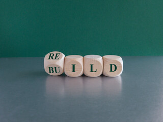 Rebuild symbol. Concept green word rebuild on wooden cubes on a beautiful grey table. Green background. Business and rebuild concept. Copy space.