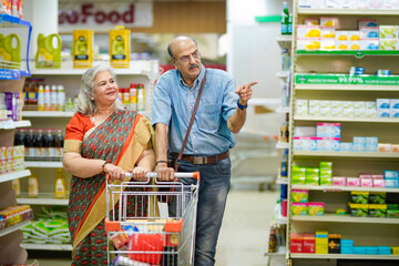 Senior indian couple purchasing together at grocery shop.