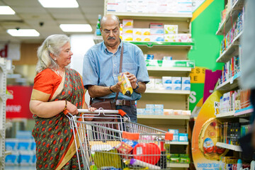 Senior indian couple purchasing together at grocery shop.