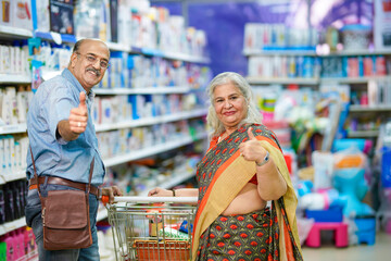 Senior indian couple showing thumps up at grocery shop.