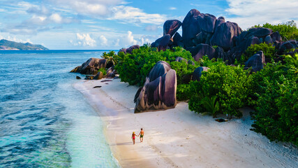 Anse Source d'Argent beach, La Digue Island, Seyshelles, Drone aerial view of La Digue Seychelles bird eye view.of tropical Island, couple men and woman walking at the beach during sunset at a luxury