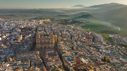Aerial view of Jaen Cathedral early in the morning. Jaen, Andalucia, Spain with foggy green hills at background. UHD, 4K - 628403218