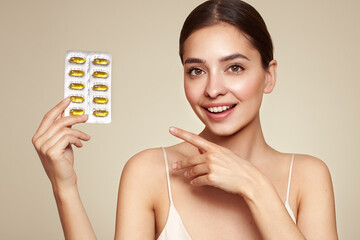 Vitamins. Close Up Of Happy Beautiful Girl With Pill With Cod Liver Oil Omega-3. Nutrition. Vitamin D, E, A Fish Oil Capsules. Healthy Lifestyle. Sport, Diet Concept - obrazy, fototapety, plakaty
