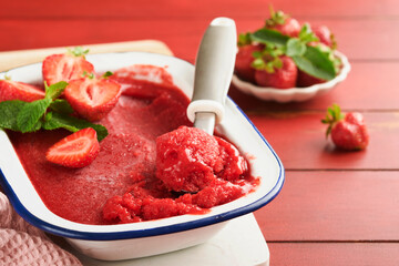 Strawberry granita or fresh berry sorbet in white rustic bowl on old wooden table background. Ice cream with strawberry and mint. Summer treat. Top view.