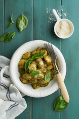 Potato gnocchi. Traditional homemade potato gnocchi with sauce pesto, kitchen table and basil on old rustic turquoise kitchen table. Traditional Italian food. Traditional Italian food. Top view.