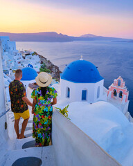 A couple walking at the village of Oia Santorini Greece, men and women visit the whitewashed Greek village of Oia during summer vacation - obrazy, fototapety, plakaty