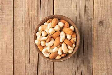 Large assortment of nuts in different bowls on stone table.