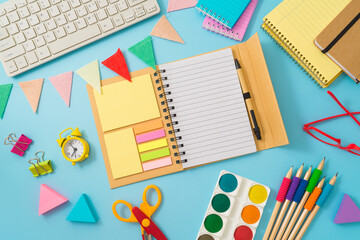 Back to school concept with notebook, school supplies and computer keyboard on blue background. Top view, flat lay