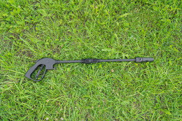Handle and sprayer of a high-pressure washer on green grass