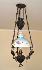 Antique chandelier with black iron construction decorated with three iron parrots and hand painted glass lampshade with floral motif