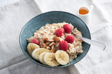Oatmeal porridge bowl with banana, raspberries, nuts. Healthy vegan breakfast meal