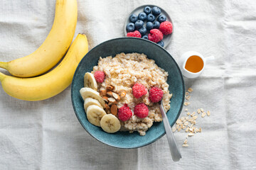 Healthy breakfast. Oatmeal porridge with banana slices, raspberries and almonds in a bowl, top view. Diet meal - 628414420