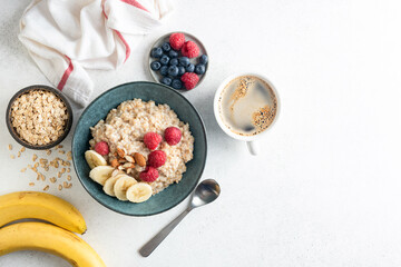 Obraz na płótnie Canvas Vegan oatmeal bowl with almonds, raspberries and banana on grey concrete table background, Top view, Copy space