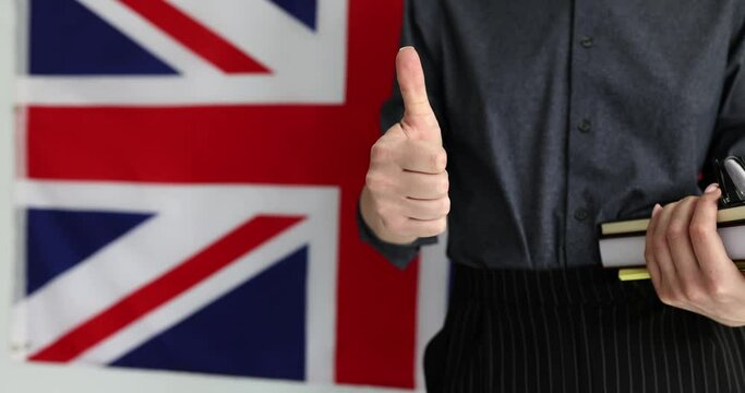 Woman holding UK flag textbooks and showing thumbs up. Higher education in England for foreigners