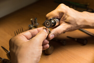 Close-up of a jeweler's hands polishing a gold ring.