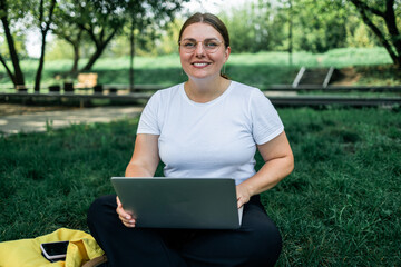 Portrait of smile student in smart casual using digital laptop outdoors in urban park background. Business people concept.