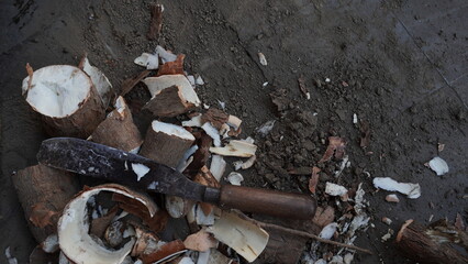 a large knife with a wooden handle, placed on a pile of cassava, peeled skin, the pile of cassava with skin that has been peeled