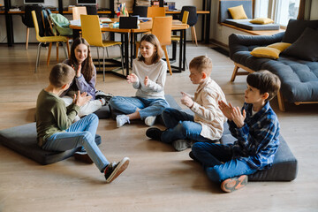Group of children clapping hands while sitting in library