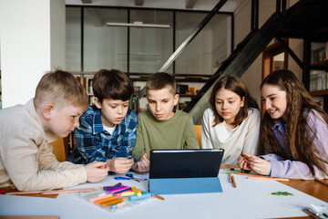 Group of kids watching something on tablet while sitting in library