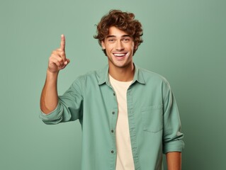 Portrait of a fictional young guy pointing finger up isolated on a plain colored background. Generative AI.