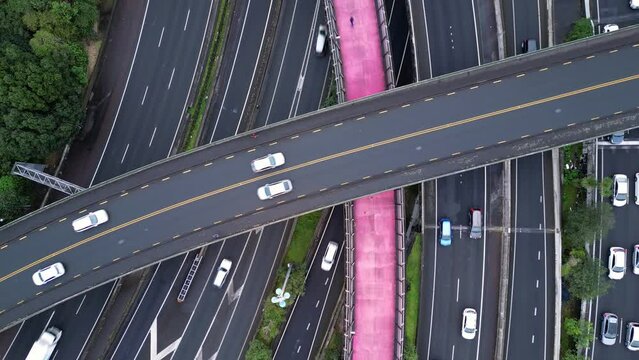 Auckland, New Zealand: Overhead drone footage of the famous pink cycleway in the middle of a multi lanes highway with heavy traffic in Auckland. Shot with an upward motion