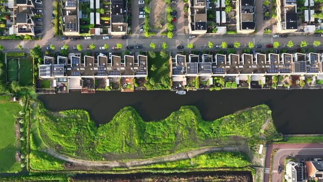 Aerial birdseye view of rows and rows of new houses near a waterway on a beautiful golden evening in summer