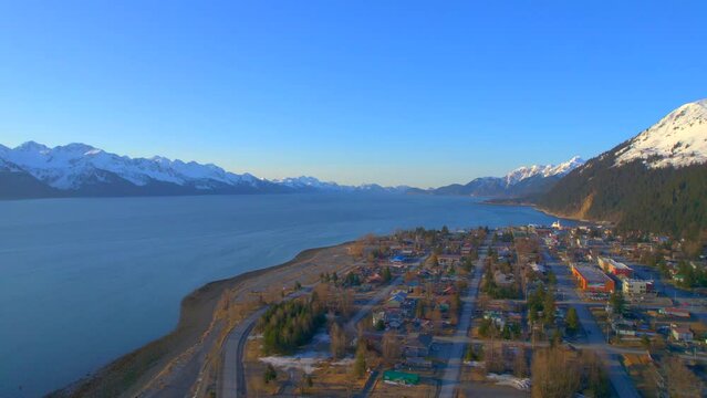Side to side aerial view of downtown Seward Alaska and the mountains at sunrise.