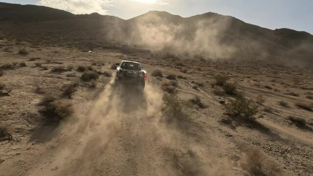 FPV drone captures off-road race truck conquering desert dirt trails with thrilling speed and precision. Intense off-roading adventure!