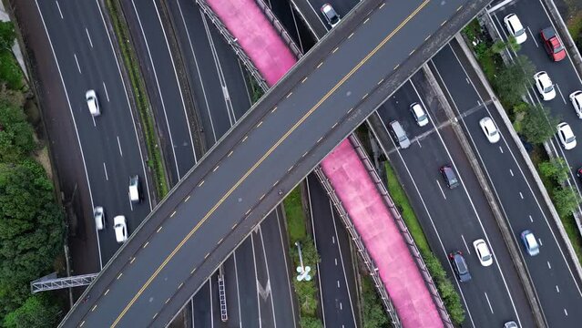 Auckland, New Zealand: Overhead drone footage of the famous pink cycleway in the middle of a multi lanes highway with heavy traffic in Auckland. Shot as a time lapse video with a rotation motion