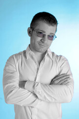 Obraz premium Ein kurzhaariger Mann mit Sonnenbrille im weißen Hemd verschränkt die Arme