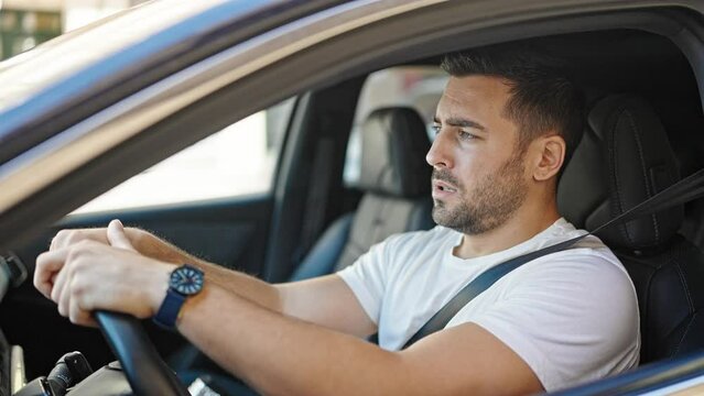Young hispanic man stressed driving car at street