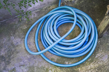 Blue garden watering hose reel laid on plastered cement floor for water the plants and washing car...