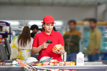 Indian female cashier scanning grocery item at supermarket.