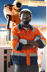 Multiracial engineer working with robot automation maintenance technology in factory, portrait. Engineering people in safety hardhat standing in background heavy industry futuristic robotic machinery