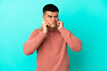 Young handsome man over isolated blue background frustrated and covering ears