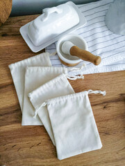 White cotton bags and utensils on a wooden table. Fabric bag mockup