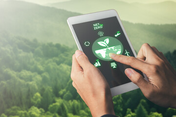 Net zero and CO2 emission reduction to stop global warming problem and reduce pollution.hand holing tablet with net zero target and carbon credit on tablet screen. - obrazy, fototapety, plakaty