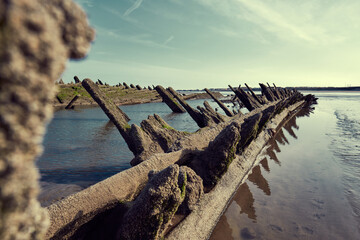 An old historic wooden shipwreck vessel carcass exposed on a desolate tropical island beach....
